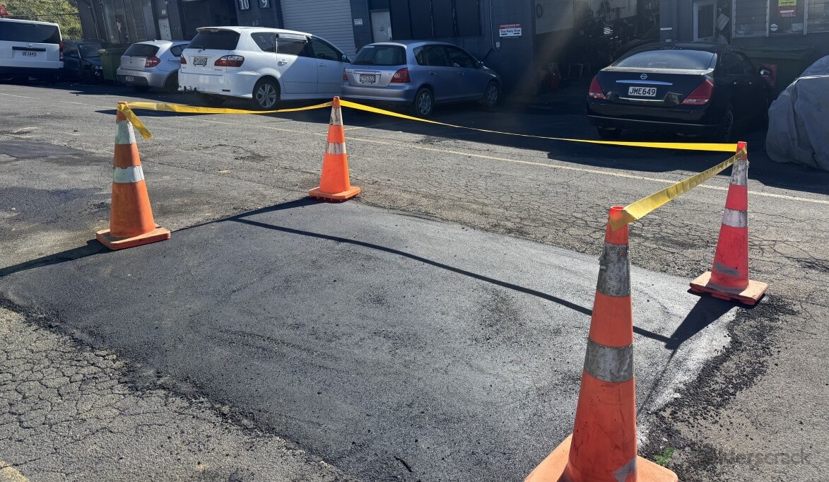 Freshly completed asphalt repair marked off with safety cones